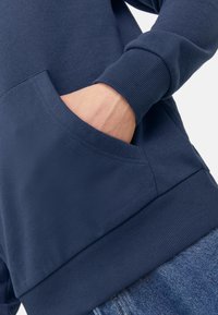 Granatowy sweatshirt z kieszenią kanguru, prążkowanym mankietami i dołem. Miękka tkanina z luźnym krojem.