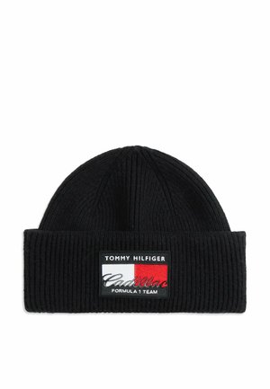 Black ribbed knit beanie with folded cuff featuring a Tommy Hilfiger Cadillac Formula 1 Team logo patch in white, red, and black colors.