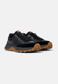 Czarne sneakersy z teksturowanej skórki i zamszu, z charakternym gumowym bieżnikiem i czerwonym logo marki na języku.