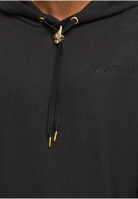 Schwarzer Kapuzenpullover mit schwarzen Kordeln, goldenen Metallenden und einem goldenen Schmetterlingsschalter, gesticktes Colucci-Logo auf der Brust.