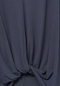 Top in tessuto leggero grigio scuro, con drappeggio morbido e dettaglio annodato in vita. Texture morbida, senza motivi visibili o hardware.