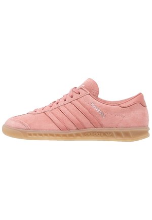 Niskie różowe zamszowe buty sportowe Adidas Hamburg z gumową podeszwą, trzema bocznymi paskami i wiązaniem na sznurowadła, pokazane w widoku z profilu.