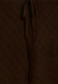 Pantalones de punto marrones con un patrón texturizado de diamantes, con una cintura elástica acanalada y un cordón ajustable para un ajuste personalizado.