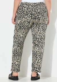 Pantaloni con stampa leopardata in beige e nero, con vestibilità slim, tasche posteriori e una texture liscia, abbinati a scarpe con piattaforma nere.