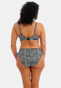Bikini à pois noir et blanc, avec un dos sans couture, des bretelles réglables et une taille évasée sur le bas pour plus de couverture.