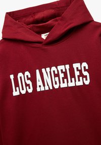 Bordowa bluza z kapturem z białym nadrukiem "LOS ANGELES" w blokowych literach. Posiada sznurek do regulacji kaptura i miękką teksturę wnętrza.