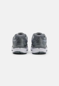 Graue Sportschuhe mit einem Obermaterial aus Mesh, gepolstertem Kragen und weißer Zwischensohle. Verfügt über strukturierte Akzente und sichtbare Markenkennzeichnung an der Seite.