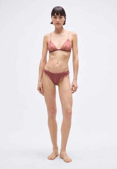 Komplet spodnjega perila v barvi pražene vrtnice, ki vključuje prosojen čipkast bralette z nastavljivimi naramnicami in ujemajoče čipkaste hlačke z detajli v valovitem robu.