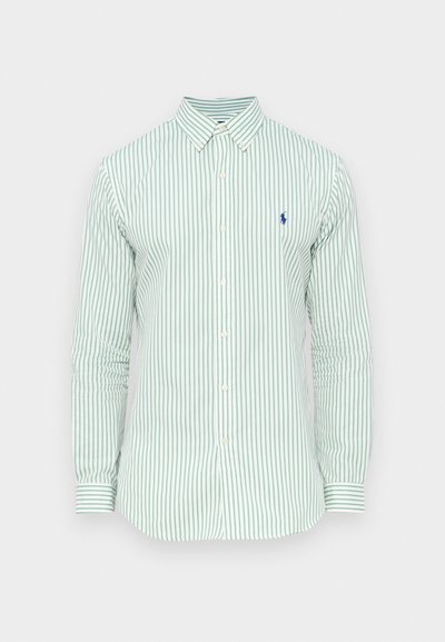 Svetlo zelena srajca z dolgimi rokavi, ovratnik na gumbe in majhnim modrim logotipom na prsih. Bombažno blago z gladko teksturo.