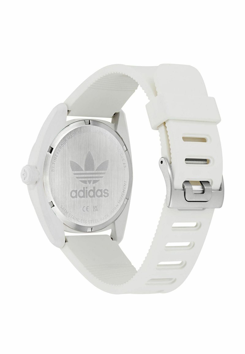 Reloj de goma blanca con caja redonda, respaldo de acero inoxidable, grabado del logo y una hebilla metálica plateada en una correa texturizada.