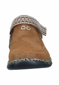 Braune Wildlederschuhe mit strukturiertem Design, ausgestattet mit einem dekorativen Riemen und kontrastierenden Nähten. Niedrigprofilierte schwarze Gummisohle.