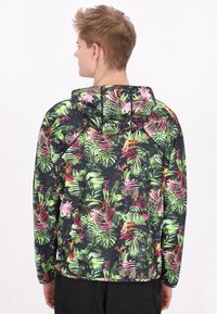 Kapuzensweatshirt mit einem lebhaften, mehrfarbigen tropischen Blattmuster auf schwarzem Hintergrund, aus leichtem, strukturiertem Material.