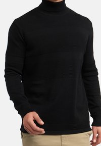 Svart polokrage-sweater med strukturerade horisontella ränder. Har en figurnära design, långa ärmar och ribbade ärmslut och nederkant.