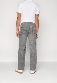 Šedé džíny v uvolněném střihu, s dvěma zadními kapsami a malým logem. Skvěle se hodí k bílým teniskám a jednoduchému tričku.