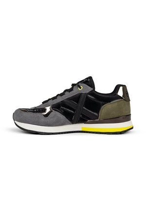 Zapatillas deportivas que presentan una combinación de ante gris y piel sintética negra, con acentos en verde lima, superposiciones texturizadas y una suela acolchada.