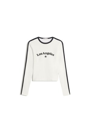 Weißes Langarmoberteil mit schwarzem Saum, das "Los Angeles" und ein Stern-Graphic auf der Vorderseite aufgedruckt hat. Aus Baumwollmaterial, in gekürztem Design.