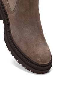 Bottine en suede marron avec un bout arrondi, surface texturée et une semelle en caoutchouc épaisse avec un motif strié.