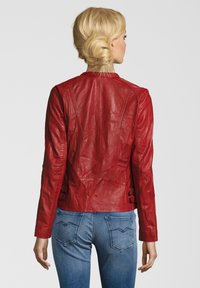 Rote Lederjacke mit tailliertem Design, ausgestattet mit Schulternähten und zwei verstellbaren seitlichen Schnallen. Glatte Textur mit einem eleganten Erscheinungsbild.