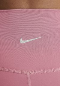 Nike rosa leggings med ett slätt och elastiskt tyg. Har en reflekterande logotyp och platta sömmar som framhäver en åtsittande och strömlinjeformad design.