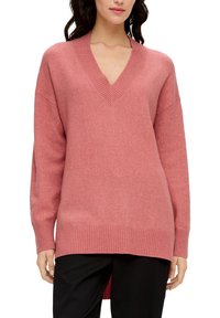 Pull rose oversize avec col en V et ourlet côtelé. Caractérisé par des manches longues, une texture douce et une coupe ample.