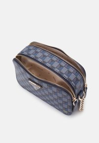 Blau gemusterte Tasche mit geometrischem Design, ausgestattet mit einem doppelten Reißverschluss und einem Signaturlogo. Das Innere besteht aus beigem Stoff mit minimaler Markenkennzeichnung.