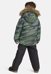 Mustriga isoleeritud jope rohelise ja halli disainiga, faux karvadega kapuutsi ning elastsete mansettidega, koos mustade pükstega.