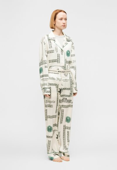 Λευκή πιτζάμα με σχέδιο χαρτονομισμάτων σε πράσινο και μαύρο, με τοπ με γιακά και παντελόνια φαρδιάς γραμμής. Απαλή υφή υφάσματος.
