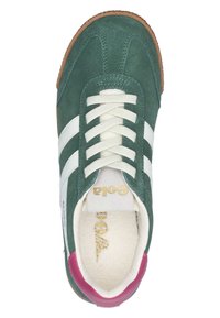 Zapatilla de ante verde con rayas de cuero blanco, puntera redonda, cordones beige, acento en el talón rosa, suela de goma texturizada y detalle del logo en dorado.