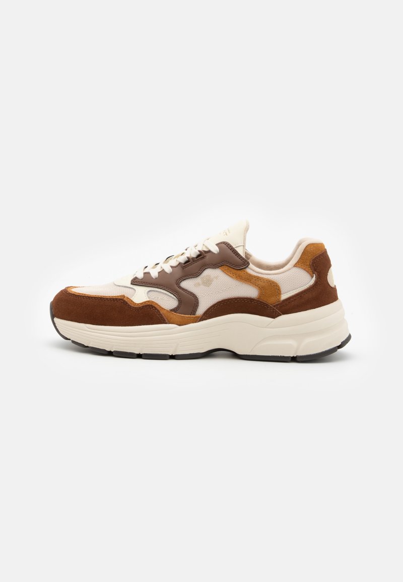 Sneaker with a beige mesh upper, brown and tan suede accents, and a thick cream sole. Features laces and a textured design on the side.