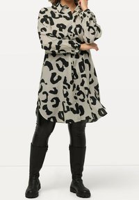 Beige shirt-jurk met luipaardprint en zwarte vlekken, met een kraaghalslijn, knoopsluitingen, lange mouwen en een gebogen zoom.