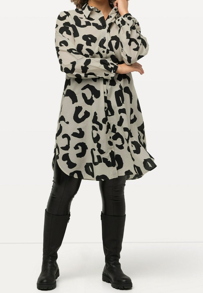 Beige shirt-jurk met luipaardprint en zwarte vlekken, met een kraaghalslijn, knoopsluitingen, lange mouwen en een gebogen zoom.