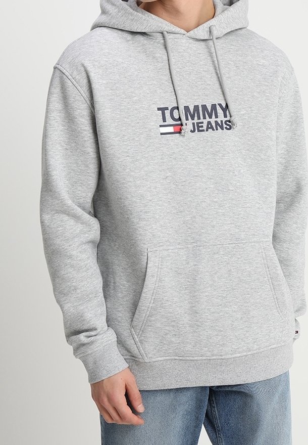 Sudadera de algodón gris con cordones, que presenta un logotipo en navy y rojo de "TOMMY JEANS" en el frente y un bolsillo canguro. Puños y dobladillo acanalados.