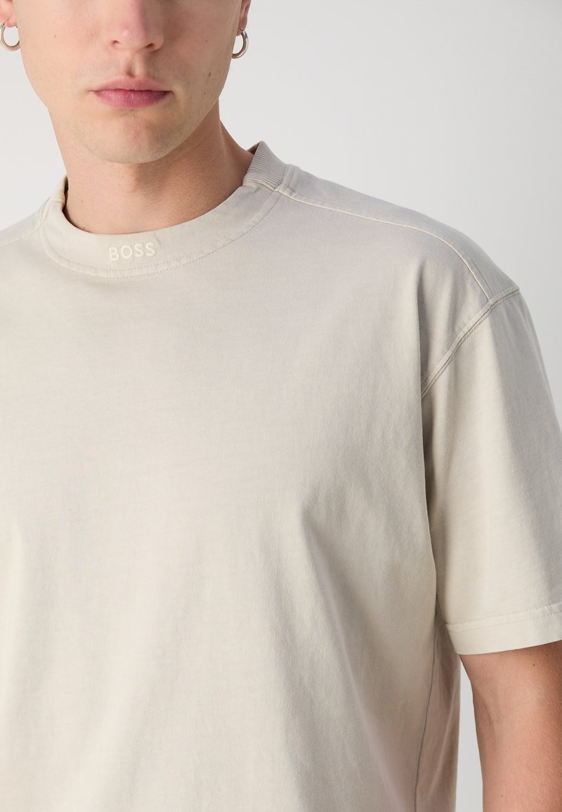 Beige katoenen t-shirt met een ribbelachtige ronde hals, met het BOSS-logo geborduurd op de halslijn en een relaxte fit met korte mouwen.