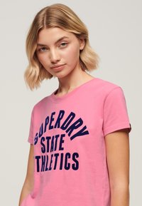 Superdry Varsity Flocked T-shirt A Maniche Corte - Vestibilità Aderente - Colore Rosa Fluorescente (Fluro Pink) - Taglia S - copertina