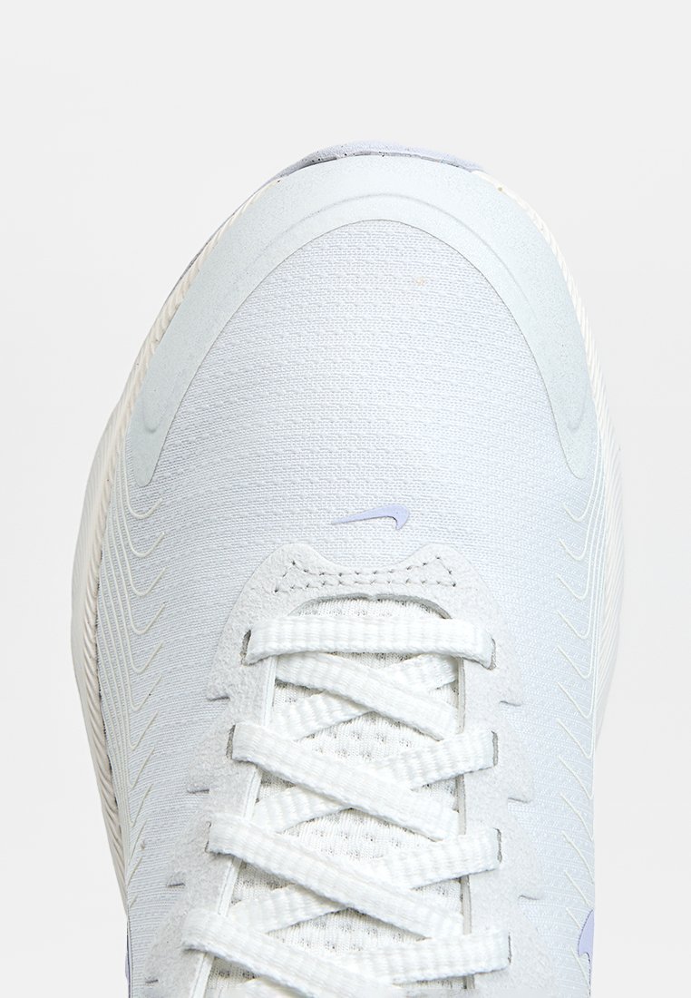 Zapatilla azul clara con un upper de tejido texturizado, cordones blancos y un logo púrpura sutil. Presenta una punta redondeada y un diseño aerodinámico.
