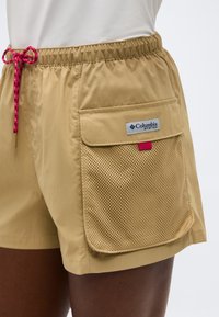 Μπεζ σορτς με ελαστική μέση και κόκκινο κορδόνι, με μεγάλη δίχτυ τσέπη και ετικέτα Columbia PFG στο πλάι.