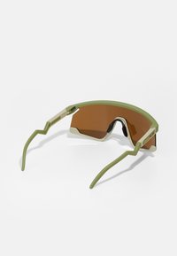 Sonnenbrille mit einem grünen Kunststoffrahmen, eckigem Design und braun getönten Gläsern. Verfügt über einzigartige Zickzackbügel und strukturierte Akzente.