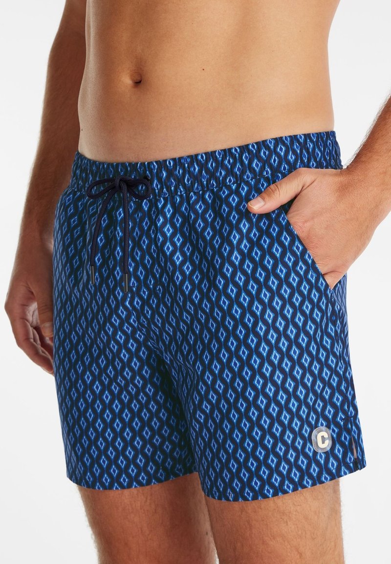 Shorts de bain bleus à motif avec un design en diamant, taille élastique avec cordon de serrage et poches latérales. Accent de logo sur l'ourlet.