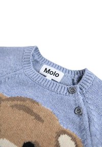 Jasnoniebieski sweter z dzianiny z beżowym wzorem zwierzęcym, okrągłym dekoltem i małymi szarymi guzikami. Metka głosi "Molo". Miękka faktura.