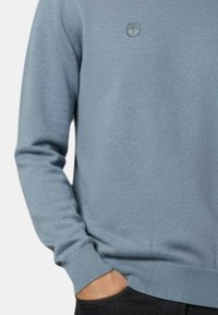 Maglione azzurro chiaro con piccolo logo ricamato, scollo rotondo, polsini e orlo a coste, realizzato in morbido tessuto a maglia.