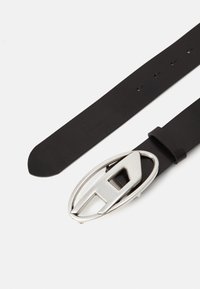 Black leather belt featuring a silver oval buckle with a cut-out design. The belt has several adjustment holes for size flexibility.