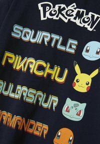 Tume sinine t-särk, millel on Pokémoni tegelased: Squirtle, Pikachu, Bulbasaur ja Charmander, koos värvilise teksti ja joonistatud kujundustega.