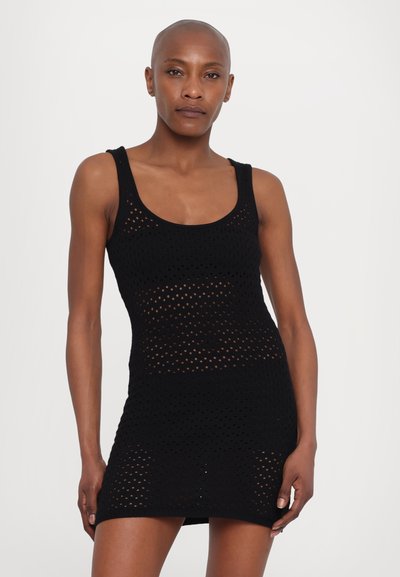 Rochie tricotată neagră cu un design fără mâneci, având modele din dantelă și o siluetă ajustată. Textură netedă și lungime până la mijlocul coapsei.