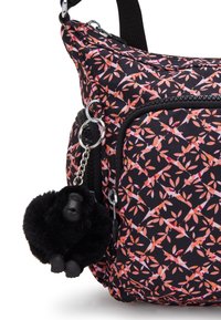 Sort taske med et blomsterprint i pink, orange og hvid. Har en frontlomme med lynlås og en sort gorilla-figur nøglekæde.