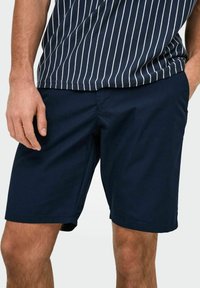 Shorts bleu marine avec une texture lisse, des poches avant et une coupe classique, associés à une chemise à rayures bleues et blanches à manches courtes.