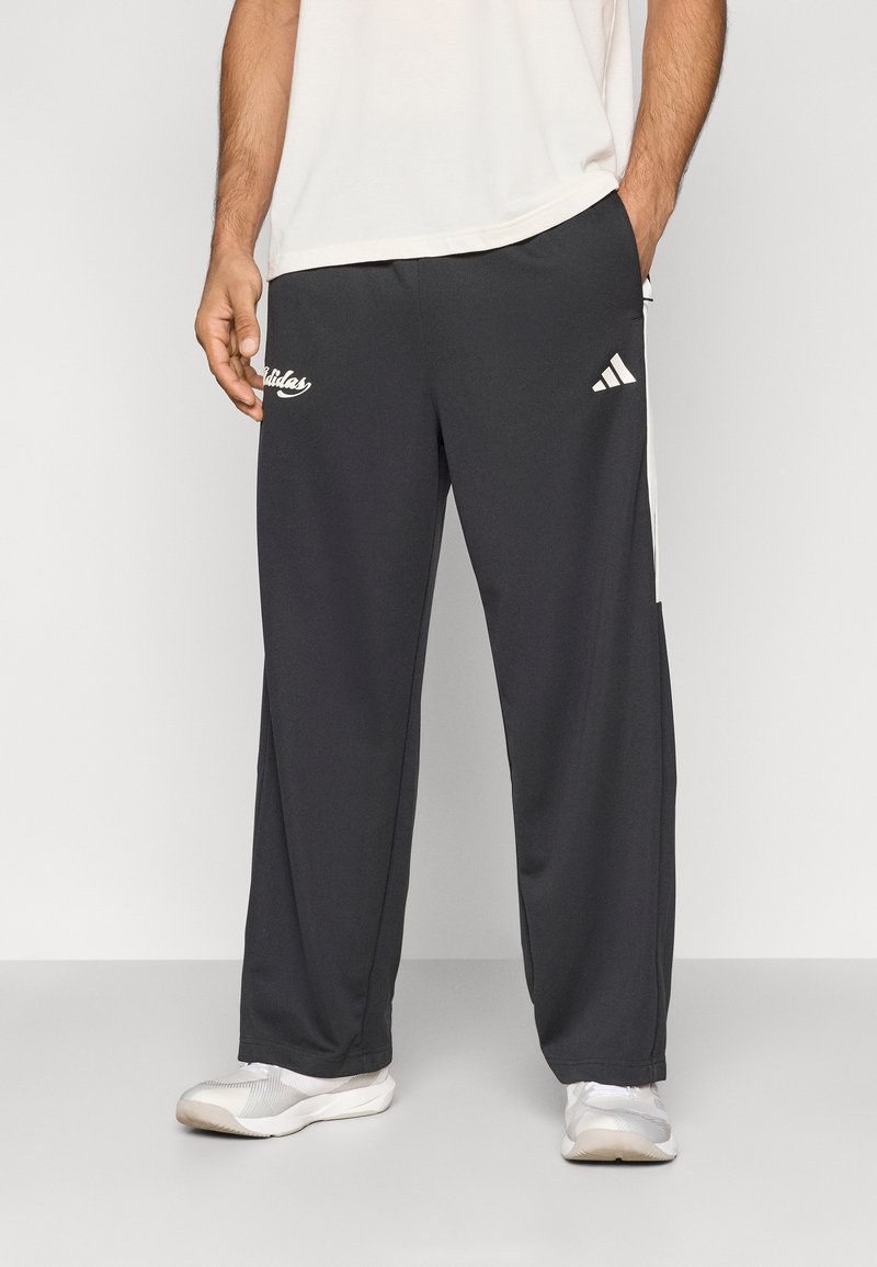 Fekete sportnadrág fehér Adidas logóval és oldalsávokkal, könnyű anyagból készült, kényelmes fazonú és egyenes szárú.