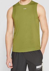 Débardeur de sport sans manches vert olive en tissu léger, avec un col rond et un logo sur la poitrine. Short noir présenté en dessous.