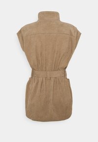 Ärmellose beigefarbene Cordweste mit hohem Kragen und passendem Gürtel, der in der Taille cincht, von hinten auf einem weißen Hintergrund gezeigt.