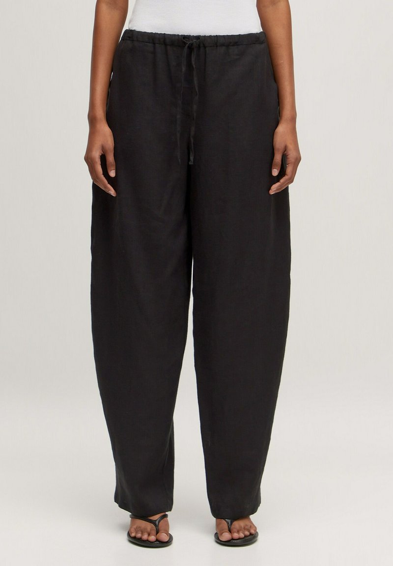 Zwarte linnen wijde broek met een elastische tailleband en trekkoord. Soepele textuur, lichtgewicht stof en een losse pasvorm voor comfort.
