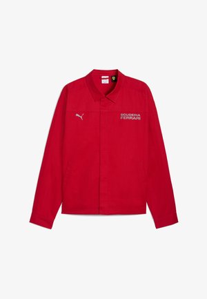 Sarkana jaka ar apkakles dizainu, kurā ir uzraksts "SCUDERIA FERRARI" un Puma logo. Izgatavota no gludas auduma, tai ir sānu kabatas.
